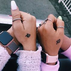 two people with matching wrist tattoos holding their hands up to the camera and pointing fingers at each other