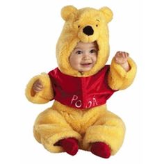 a baby in a winnie the pooh costume sitting on the floor with his hands up