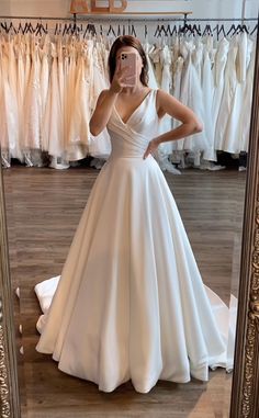 a woman taking a selfie in front of a mirror wearing a white wedding dress