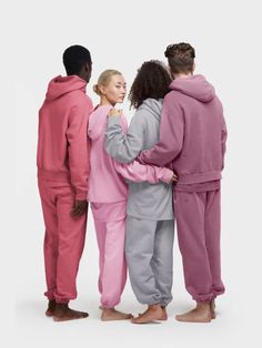 three people in pink and grey pajamas standing next to each other with their arms around one another