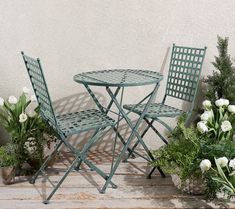 an outdoor table and chairs with potted plants