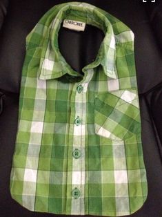 a green and white checkered shirt sitting on top of a black leather chair in a room