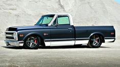 an old black pickup truck parked in front of a large rock