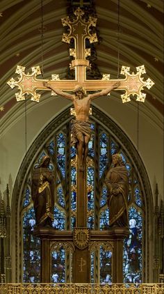 the cross is in front of an ornate stained glass window