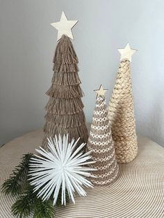 three christmas trees made out of yarn on top of a table