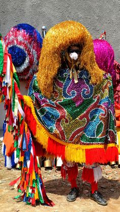 a man dressed in brightly colored clothing standing next to other colorful items on the ground