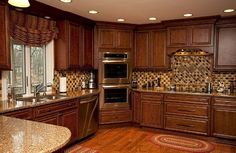 a large kitchen with wooden cabinets and granite counter tops, along with an island in the middle