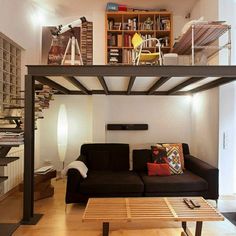 a living room filled with furniture and a loft bed next to a stair case in front of a bookshelf