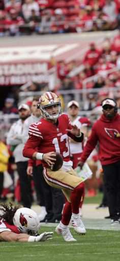 a football player running with the ball in his hand and people watching from the stands