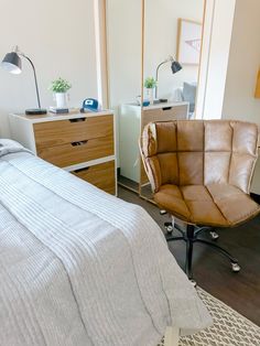 a bed room with a neatly made bed and a chair in front of the bed