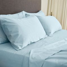 a bed with blue sheets and pillows on it