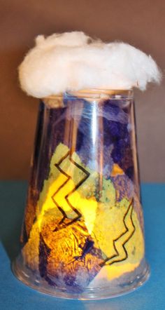 a glass vase filled with lots of different colored items on top of a blue table