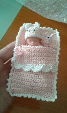 a small crocheted baby doll in a pink blanket