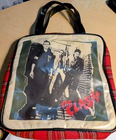 Wild and Wonderful red plaid vinyl record carry bag features Punk band The CLASH in a black and white photo. Zippered bag is sized for vinyl Lps, but I would carry it with me everyday everywhere! It's just so cool! Pretty darn unique, I've never seen another like this. Makes a great Book Bag for back to school. Also really rocks as an unusual purse. No flaws, zipper works smoothly, interior is very nice. I am in love with this! Retro Shoulder Bag For Streetwear, Zippered Bag, Punk Rock Bands, Punk Bands, The Clash, Book Bag, White Photo, Carry Bag, Rock Band