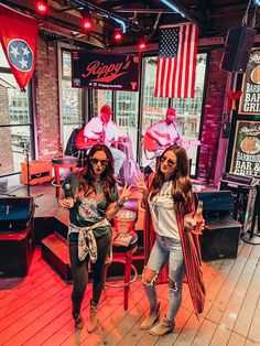 two women standing in front of a barbershop with an american flag on the wall