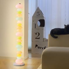 a black cat laying on top of a white couch next to a tall light pole