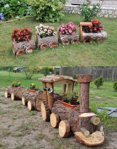 a train made out of logs with flowers in the back and on the front side