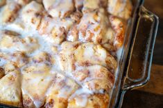 a casserole dish with cinnamon rolls covered in icing