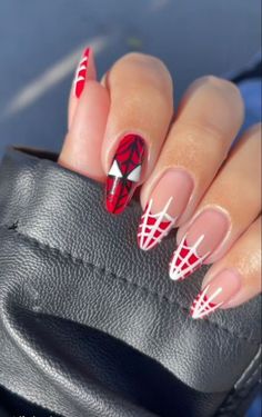 a woman's hand with red and white nail polish on it, holding a black purse