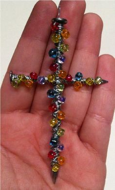 a hand holding a multicolored beaded crucifix in it's palm