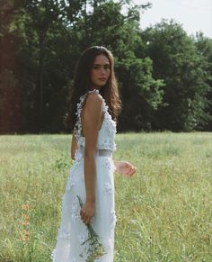 a woman in a white dress standing in a field