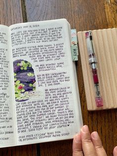 an open bible on a wooden table with a pen and eraser next to it