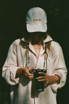 a woman wearing a white hat and holding a camera