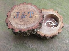 wedding rings are placed in a tree slice with the initials j and t on it