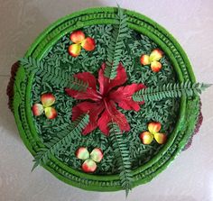 a green tray with red flowers and leaves on it, sitting on a white surface