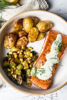 a white plate topped with salmon, potatoes and vegetables