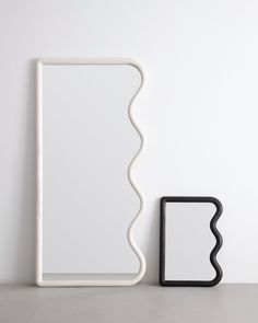 a white shelf sitting next to a black object on top of a table in front of a white wall