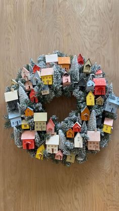 a wreath made out of small houses on top of a wooden floor next to a wall