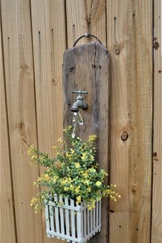 a wooden fence with a planter and water faucet mounted to it's side