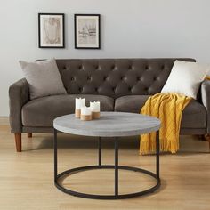 a living room with a gray couch and two candles on the coffee table in front of it