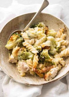 a bowl filled with pasta and broccoli on top of a white table cloth