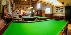 a pool table is in the middle of a room with tables and chairs around it