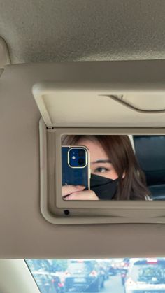 a woman taking a selfie in the rear seat of a car while wearing a face mask