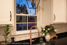 a kitchen with white cabinets, black counter tops and a large window over the sink