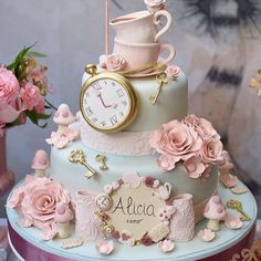 a three tiered cake decorated with pink flowers and an ornate clock on the top