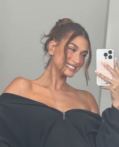 a woman taking a selfie with her cell phone while wearing a black off the shoulder top