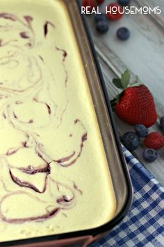 a pan filled with batter and blueberries on top of a table next to strawberries