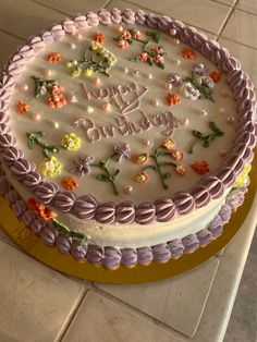 a decorated birthday cake sitting on top of a white tile floor covered in frosting