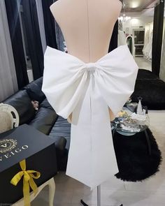 a dress form with a white bow on it's back in a living room