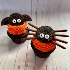 two chocolate cupcakes decorated with orange icing and googly eyes