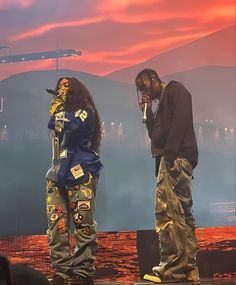 two people standing on stage with microphones in their hands