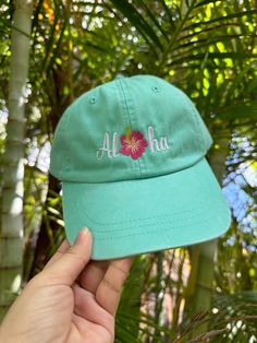 Embroidered 100% cotton low-profile dad hat with "Aloha" design and hibiscus flower center.  🧢Hat Details:  -100% Cotton - Unstructured Soft Crown Low-Fitting -Pre Curved Visor -Matching Fabric Under Visor -Metal Press Buckle 📏Size Details:  -Size: OSFM - Adult (58cm/22.8") -Low Profile: 8.25 cm - 8.4 cm / 3.2" - 3.3" 📦Shipping Details:  -all items ship in 1-2 business days 📱Follow us on Social Media:  -Instagram: @hifamilymaui -Facebook: @hifamilymaui Vacation Hats With Curved Bill In Cotton, Beach Green Cotton Baseball Cap, Green Cotton Baseball Cap For Beach, Cotton Dad Hat For Vacation, Casual Flat Bill Dad Hat For Beach, Green Short Brim Baseball Cap For Beach, Cotton Dad Hat Baseball Cap For Vacation, Green Curved Bill Baseball Cap For Beach, Green Curved Bill Baseball Cap For The Beach