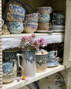 blue and white china on shelves with flowers in vases next to each other,