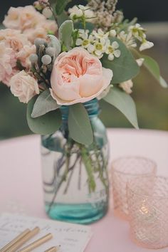 a vase filled with flowers sitting on top of a table next to glasses and napkins