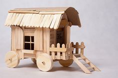 a wooden toy truck with a little house on the roof and ladders attached to it