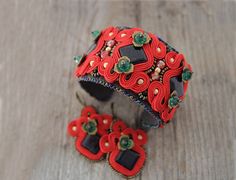 Red soutache bracelet with black stones, red beaded cuff, red jewelry set, statement bracelet, gift for her, women gift, mother day gift This red jewelry set are made with glittery black Khairo night stones (sometimes called blue sand stones), emerald glass crystals and some gold details. Red soutache bracelet and earrings makes a set, but can be bought separately: Cuff only Cuff + earrings with brass hooks Cuff + earrings with gold color hooks Cuff + earrings with silver plated hooks Cuff + ear Red Jewelry Set, Blue Sand Stone, Hand Embroidered Jewelry, Soutache Bracelet, Soutache Necklace, Mother Day Gift, Black Stones, Swarovski Bracelet, Soutache Earrings